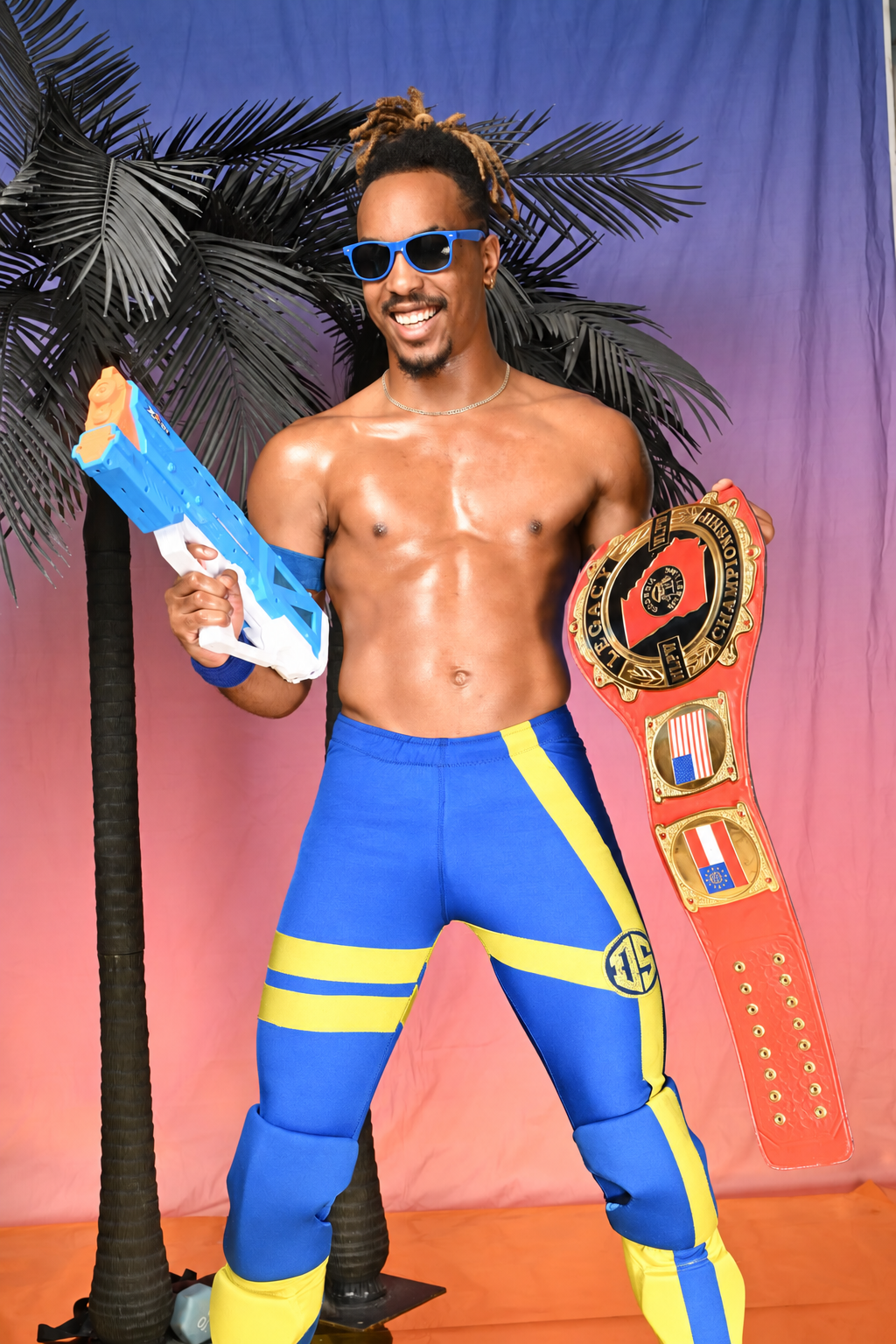 Deon Summerz in blue and yellow wrestling gear holding his championship belt