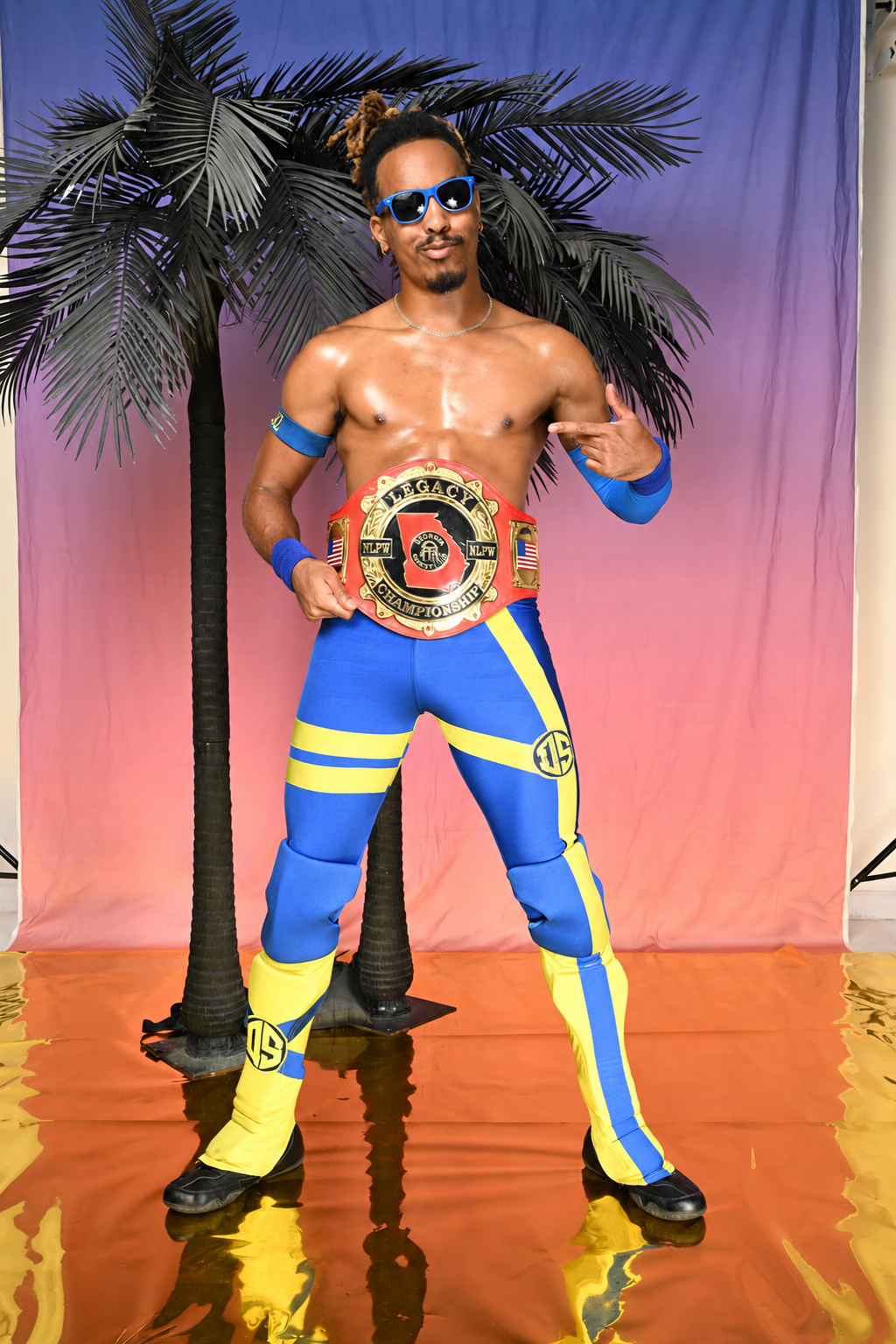 Deon Summerz wearing his championship belt with full blue and yellow wrestling gear